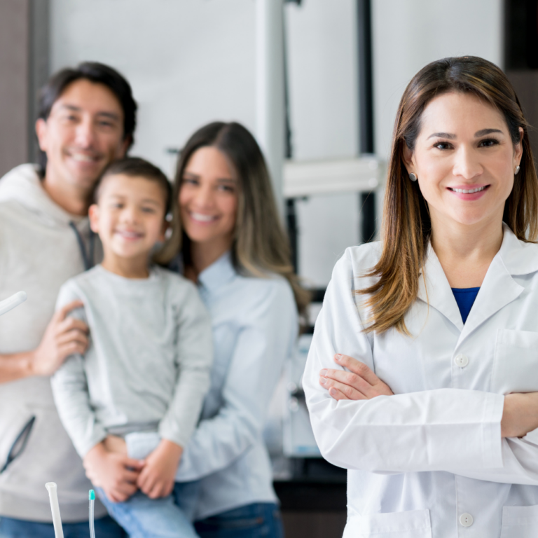 Female dentist smiling in front of family smiling